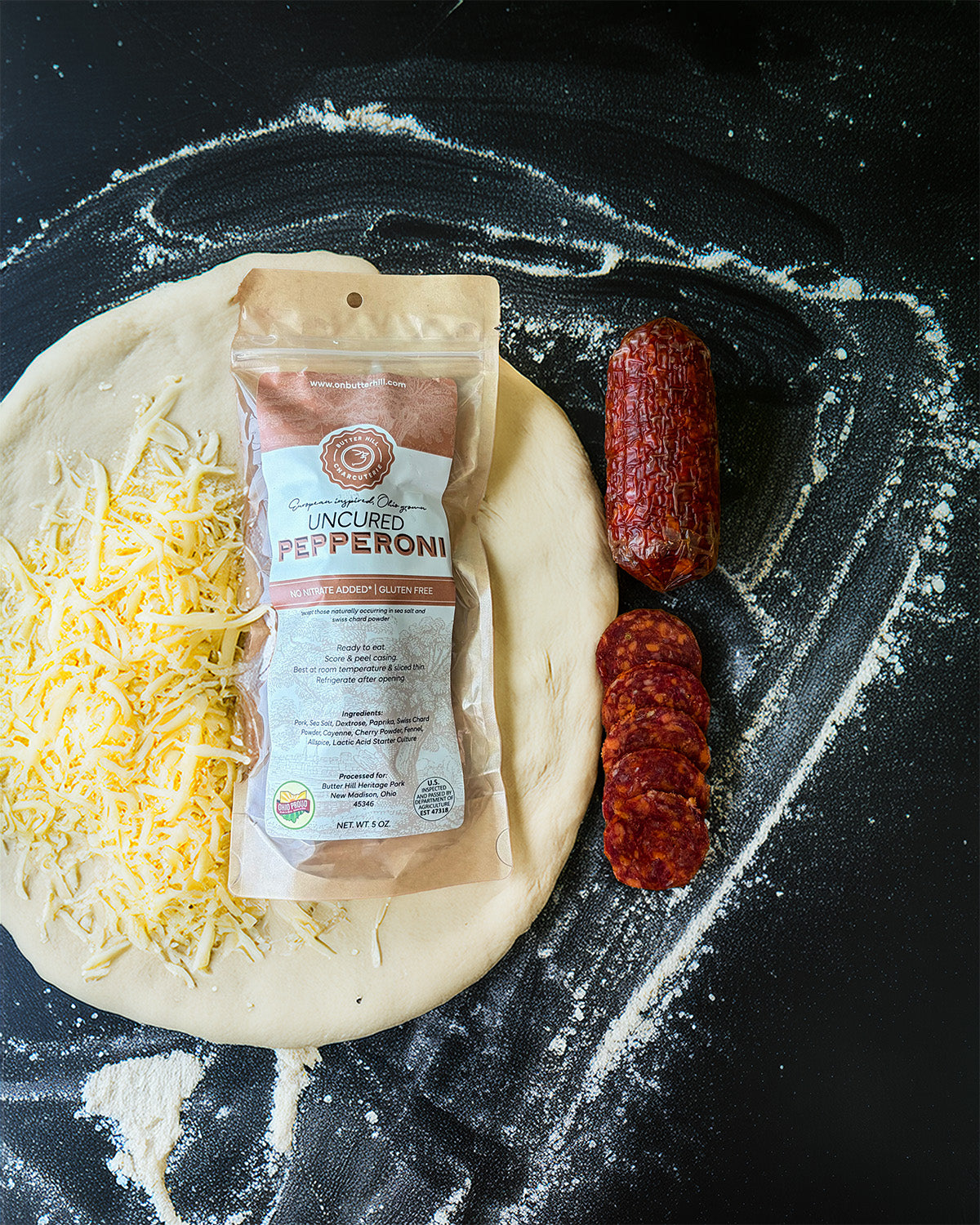 Dough with cheese and pepperoni packaging on a flour-dusted surface
